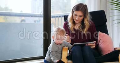 母亲在照顾婴儿时使用数码平板电脑